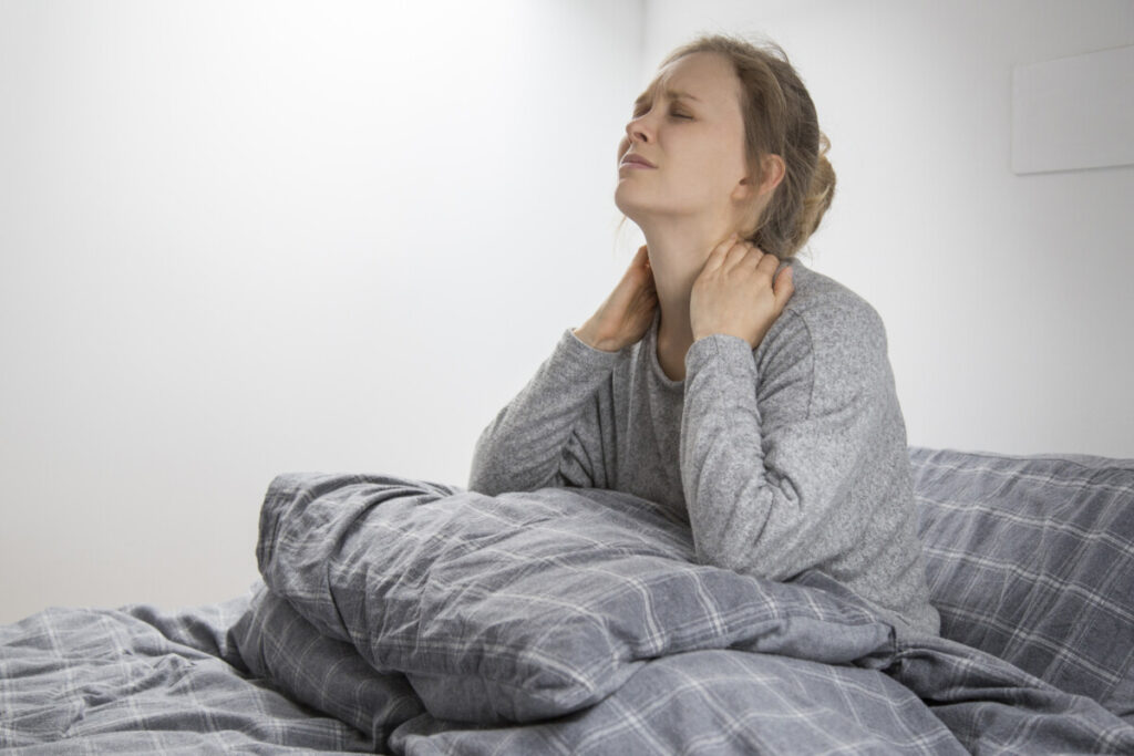 mulher sentada na cama com fibromialgia