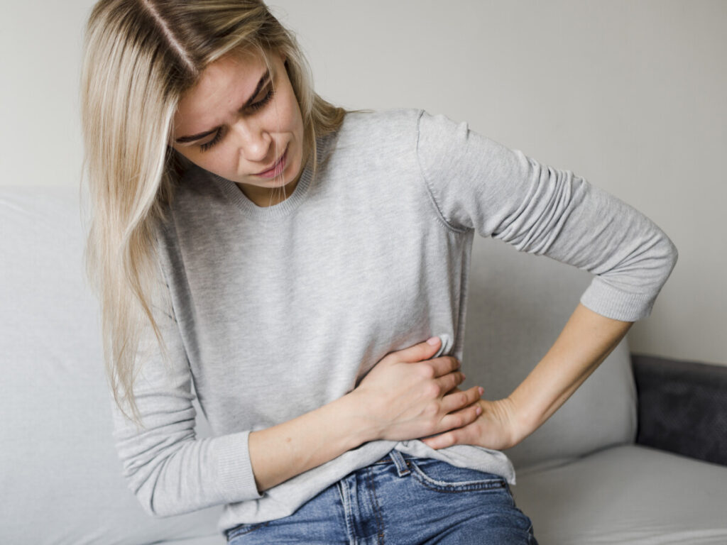 mulher sentada com dor na lateral da barriga