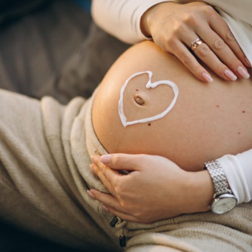 Pregnant woman applying cream on the belly to prevent stretches